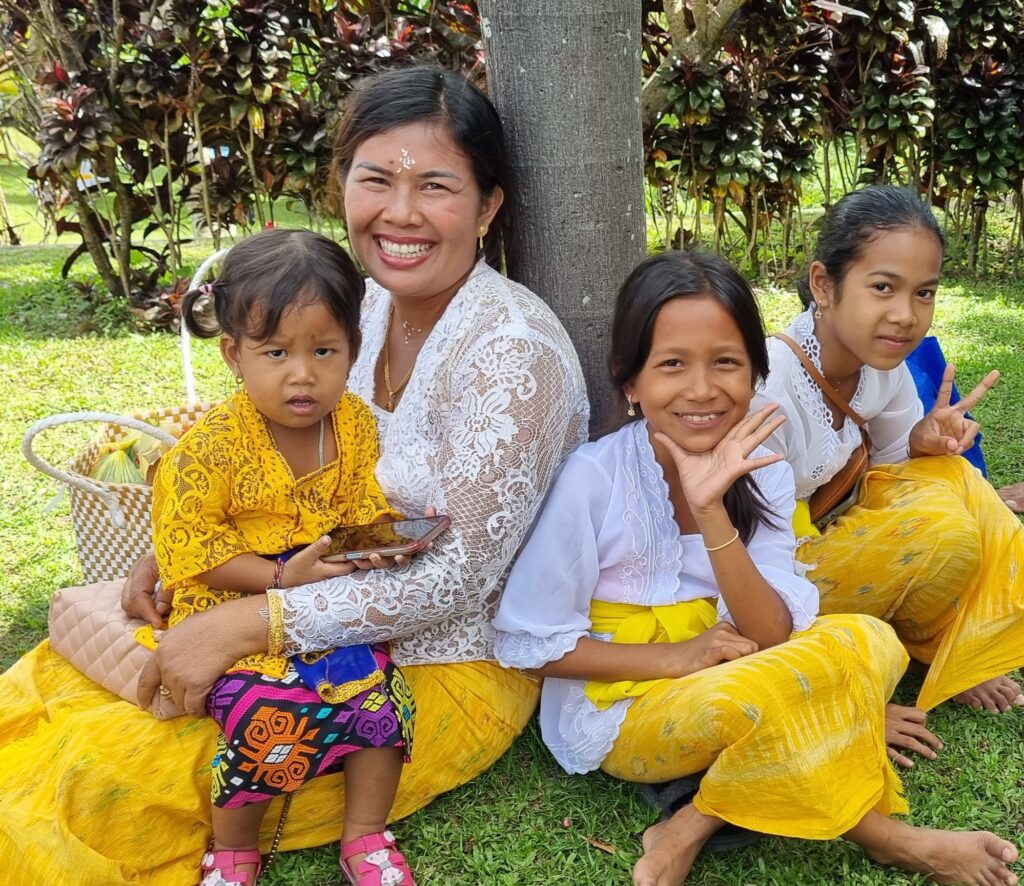 Donna e bambine balinesi in abiti tradizionali durante una festa religiosa